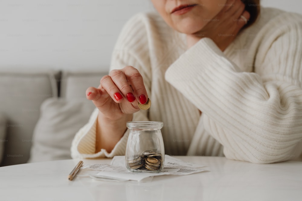 a woman sitting at a table with a jar of coins
