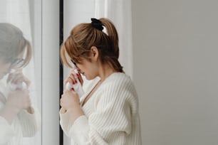 uma mulher em um suéter branco olhando em um espelho