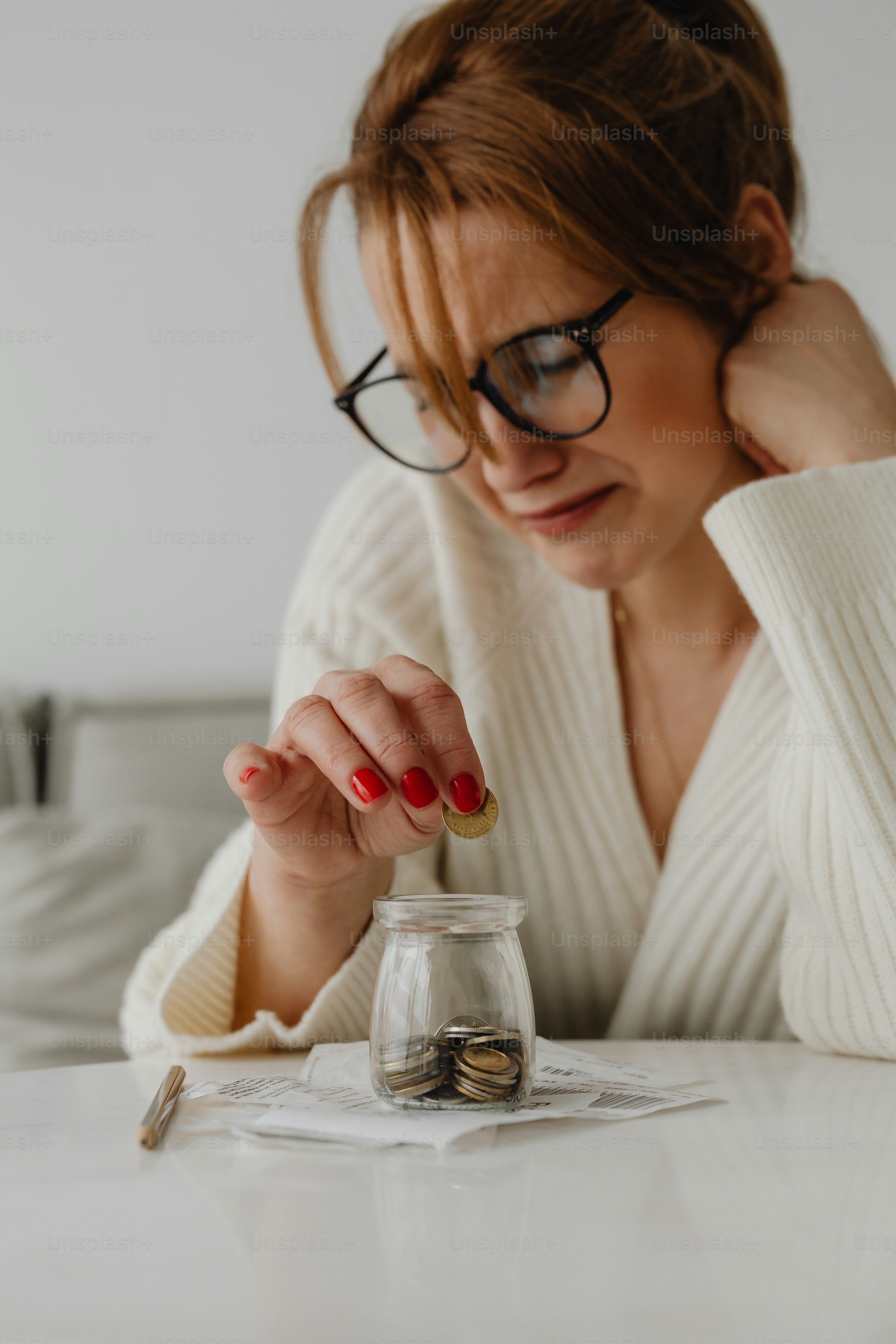 a woman sitting at a table with a jar of coins
