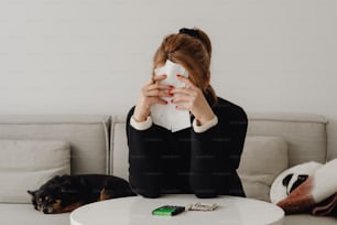 a woman sitting at a table with a napkin covering her face