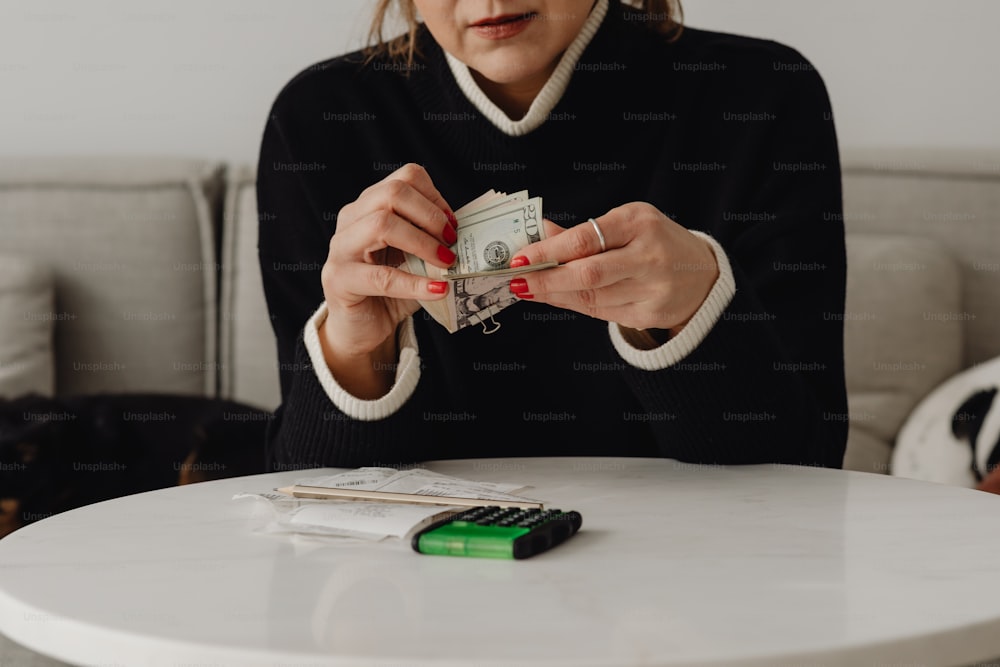 a woman sitting at a table holding a stack of money