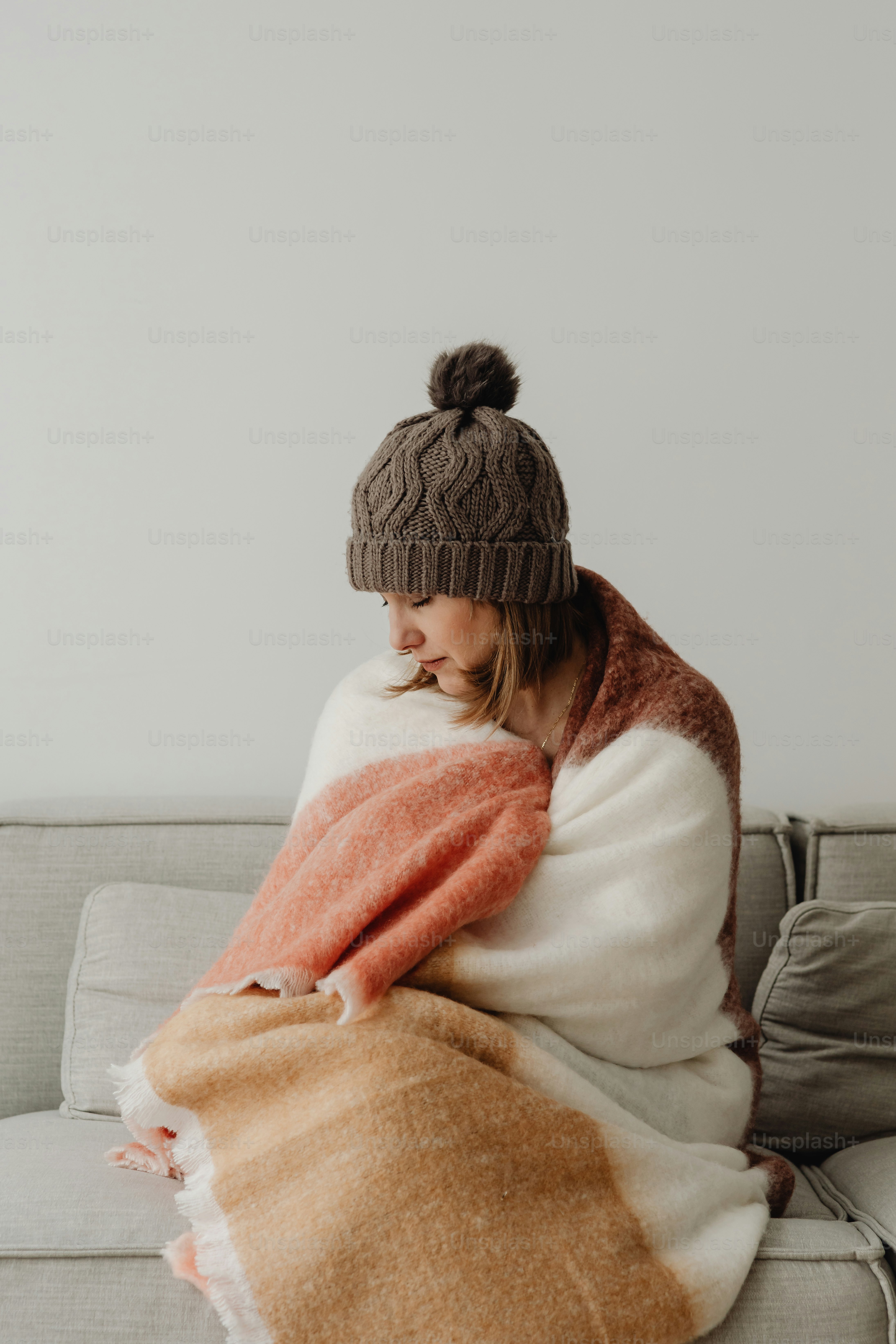 a woman sitting on a couch wrapped in a blanket