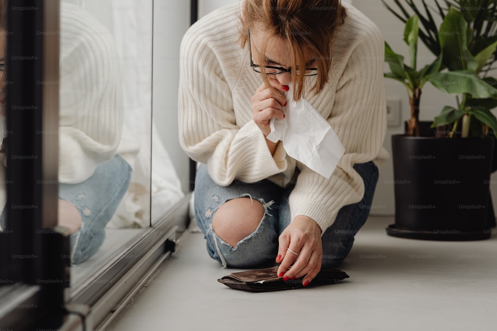 a woman sitting on the floor looking at her cell phone