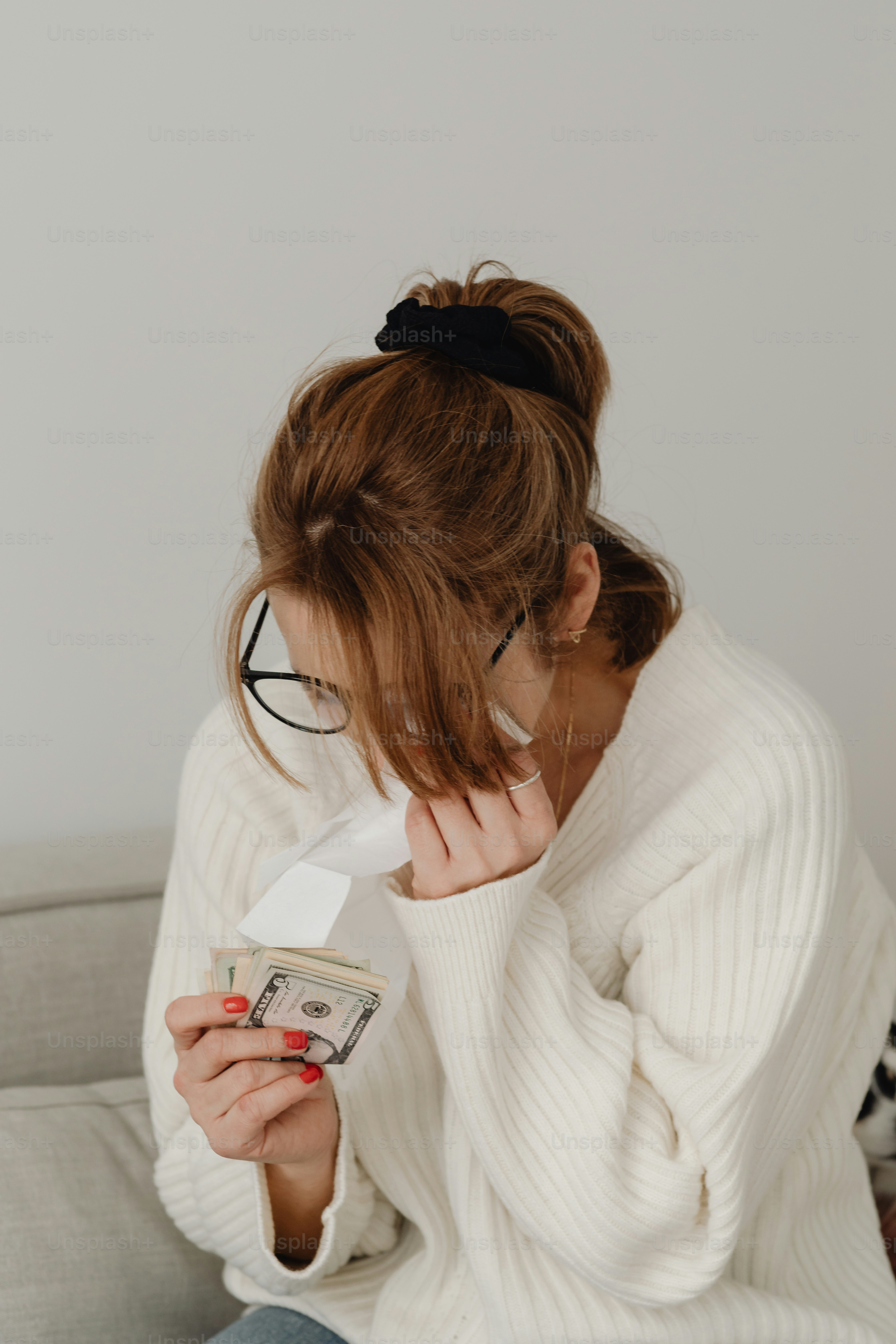 Eine Frau sitzt auf einer Couch und hält eine Schachtel Taschentücher in der Hand