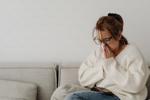 a woman sitting on a couch holding her hands to her face