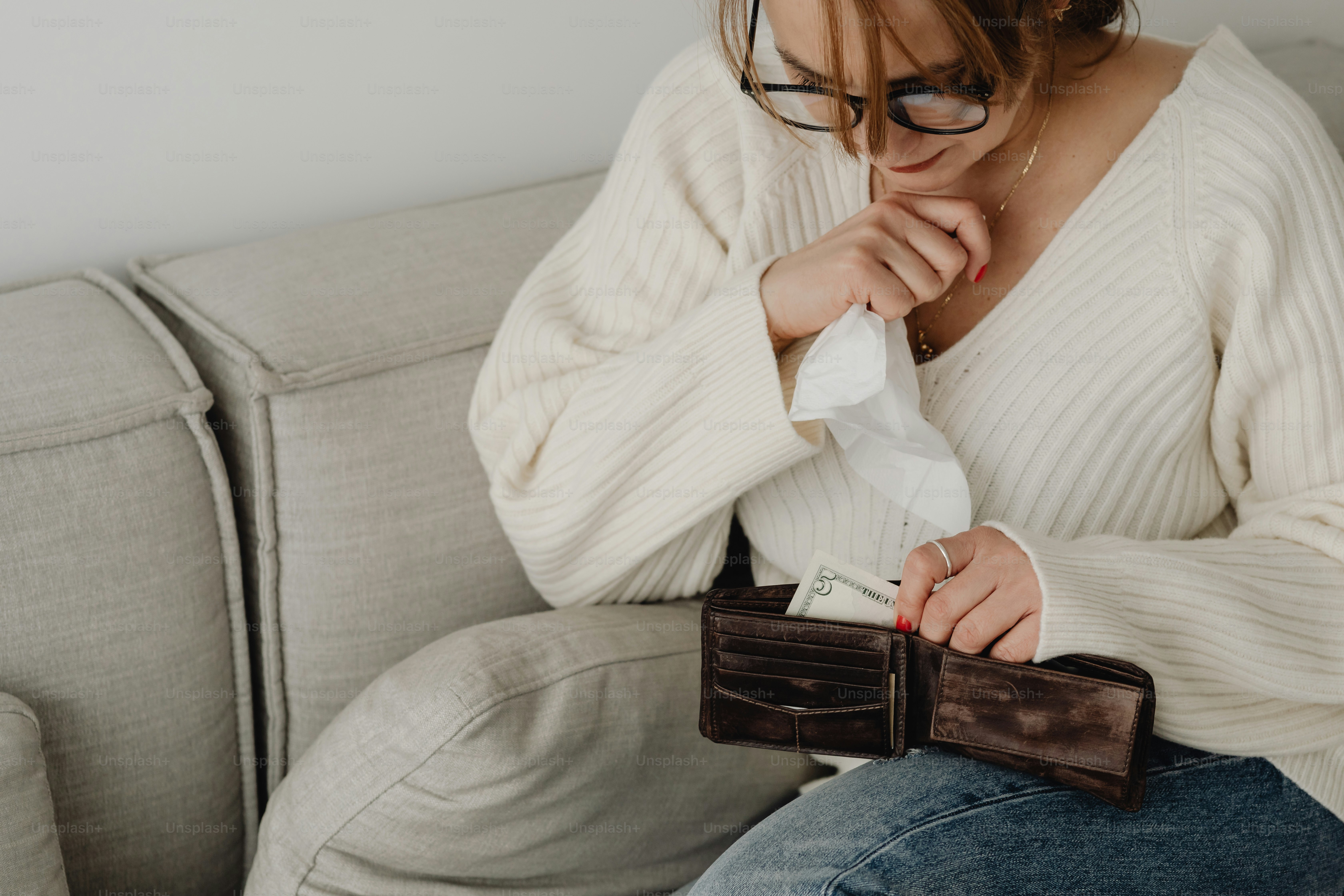 a woman sitting on a couch holding a wallet