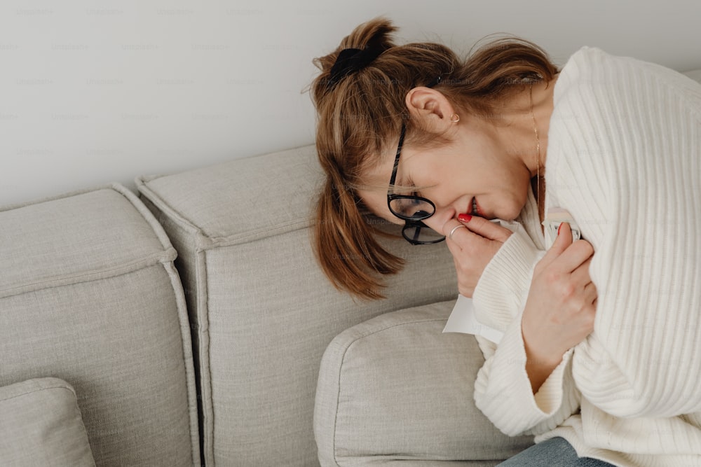 a woman covers her face while sitting on a couch