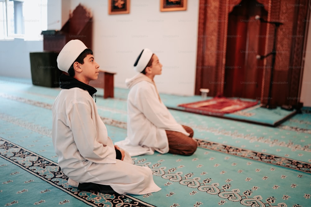 a couple of men sitting on top of a rug