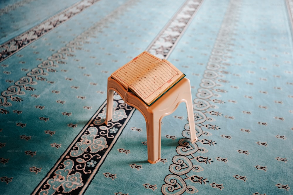 un piccolo sgabello di legno seduto sopra un tappeto