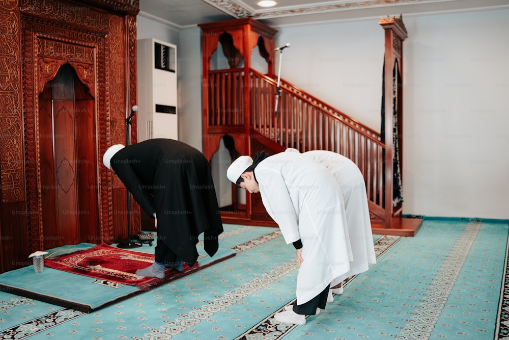 a couple of men standing over a rug on top of a floor