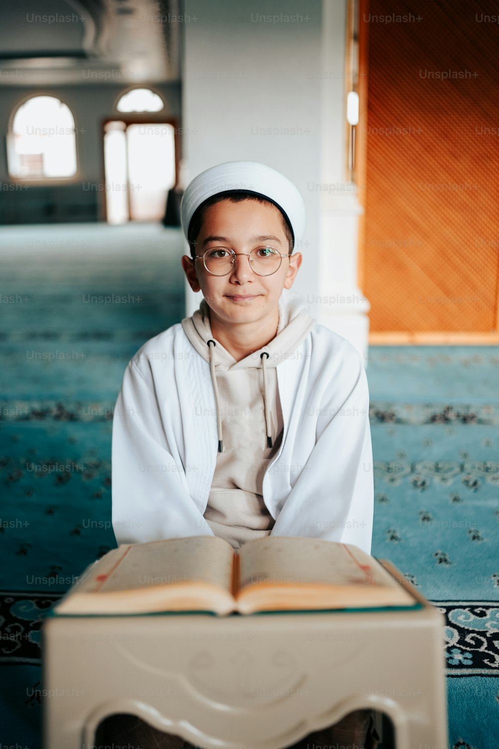 a boy in a white outfit is reading a book