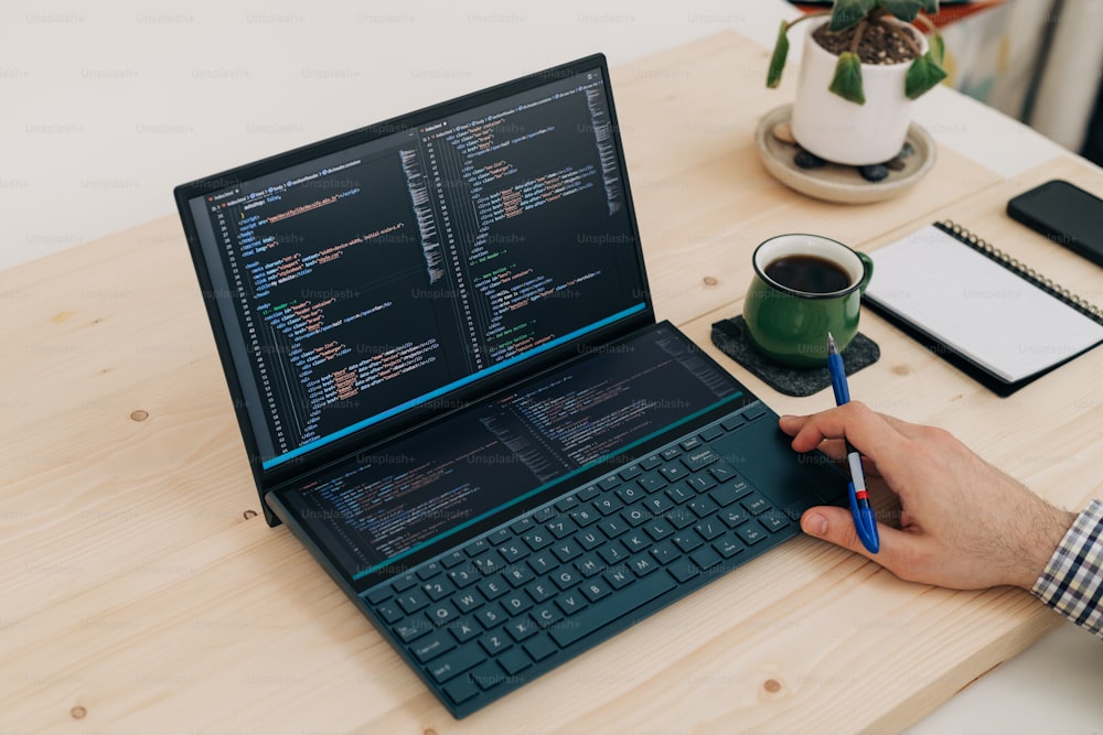 a person is writing on a laptop on a desk