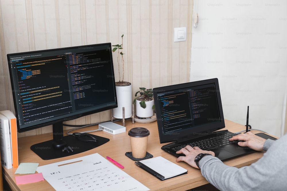 a person sitting at a desk with two computer monitors