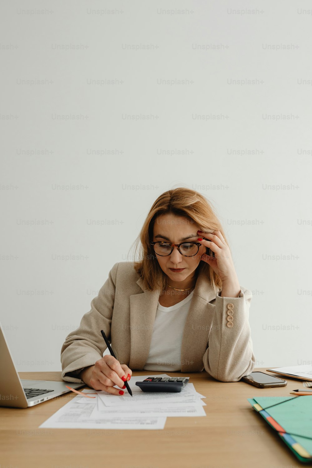 uma mulher sentada em uma mesa com um laptop e uma calculadora