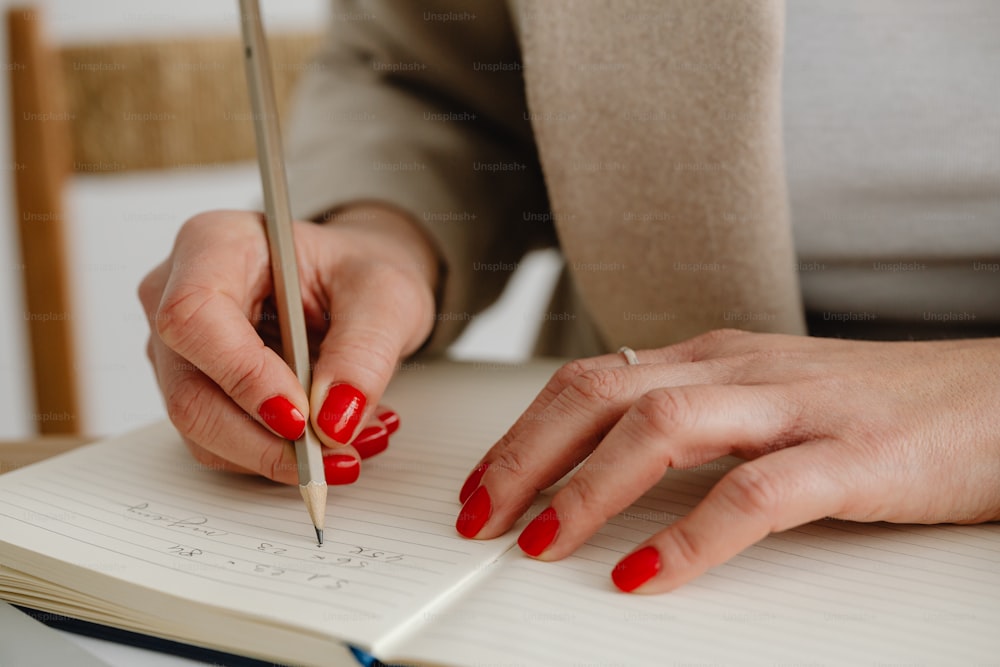 a woman is writing on a notebook with a pen
