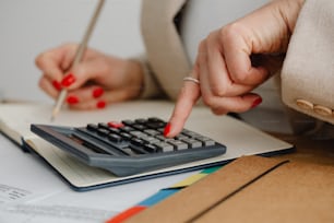 a woman is using a calculator on a desk