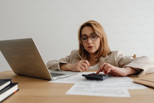 a woman sitting at a desk with a laptop and calculator