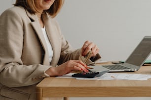 Una mujer sentada en un escritorio con una calculadora y una computadora portátil