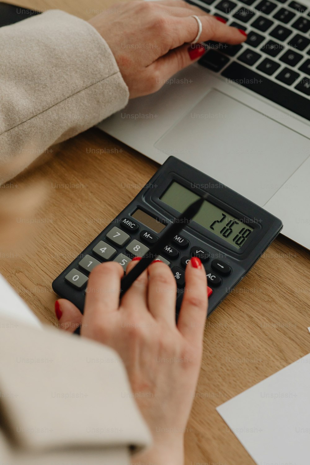 a woman is using a calculator on a desk