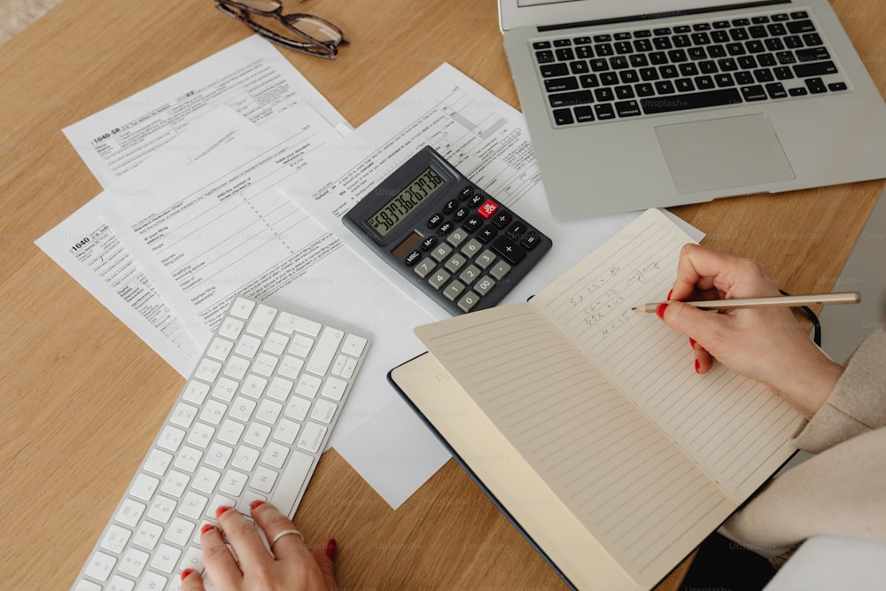 uma pessoa sentada em uma mesa com um caderno e calculadora