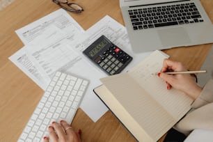 a person sitting at a desk with a notebook and calculator