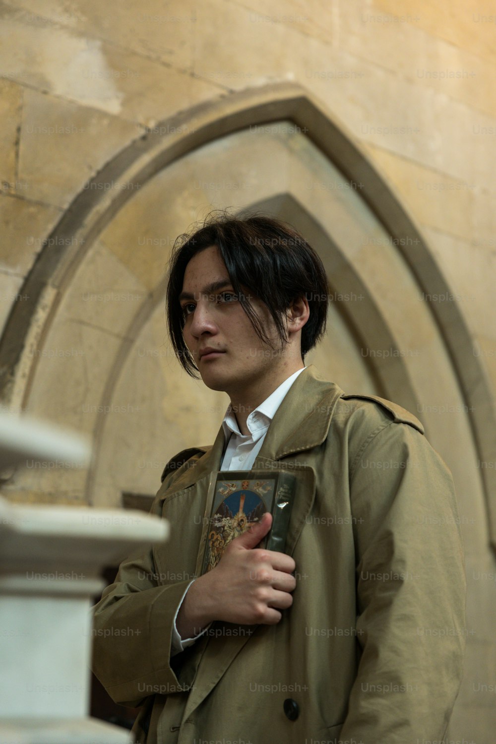 a man in a trench coat holding a book