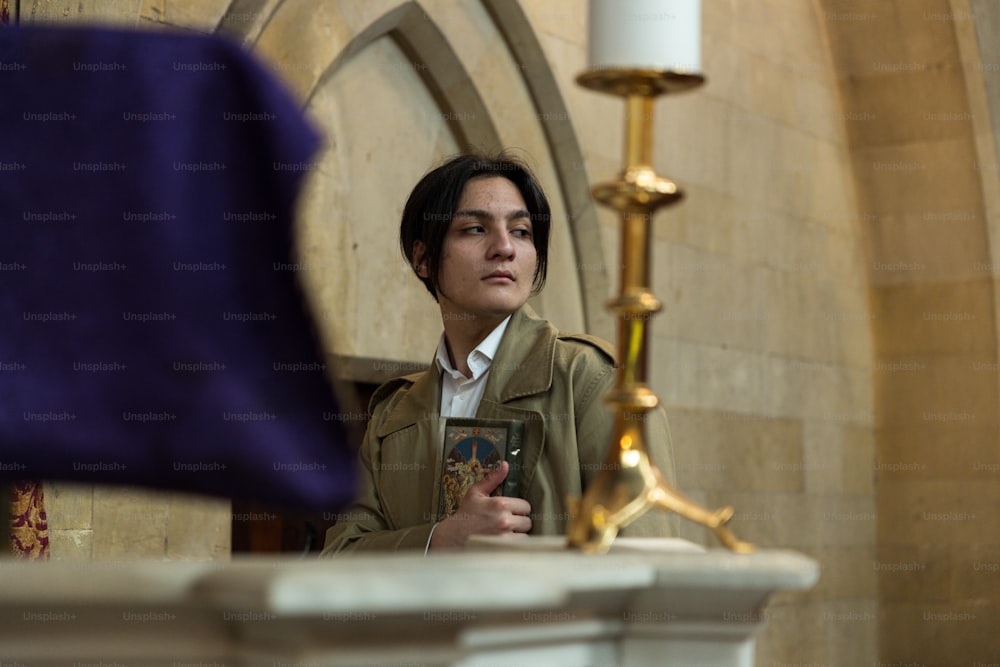 a woman holding a book in front of a candle