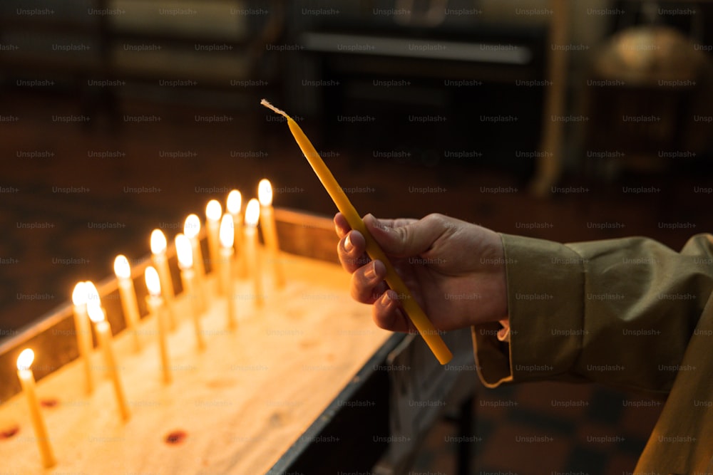 uma pessoa segurando um bastão na frente de um bolo com velas