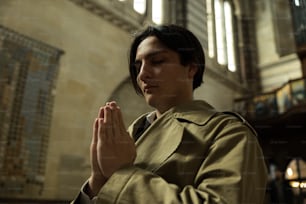 a man in a trench coat praying in a church