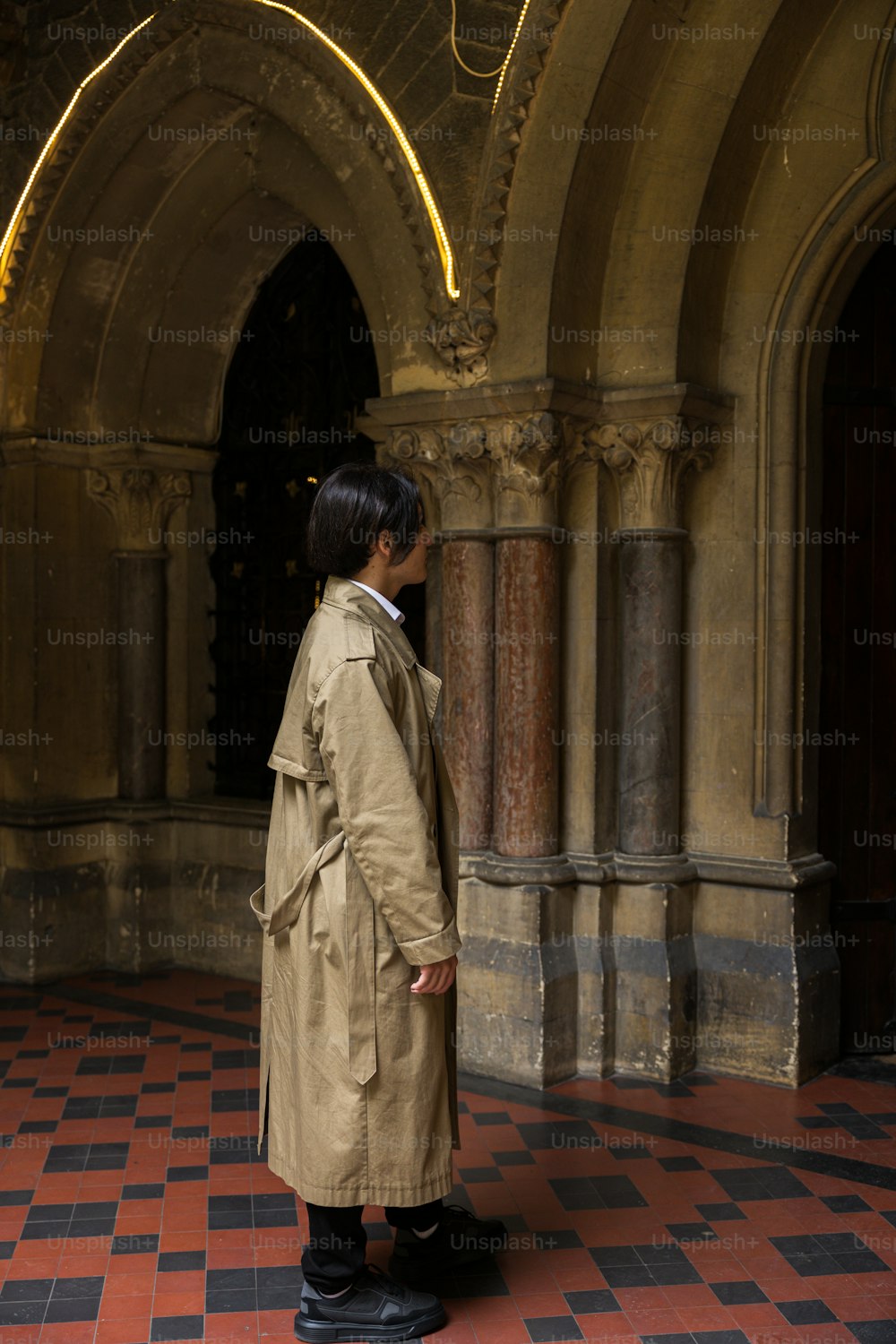 a woman in a trench coat standing in a hallway