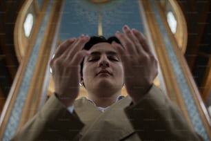 a man standing in front of a church holding his hands up