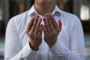 um homem de camisa branca está segurando as mãos juntas