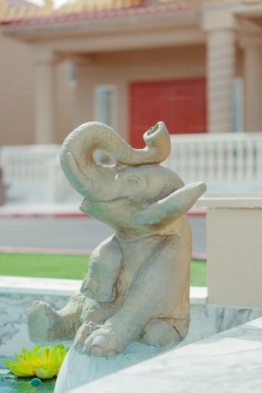 a statue of an elephant sitting next to a yellow flower