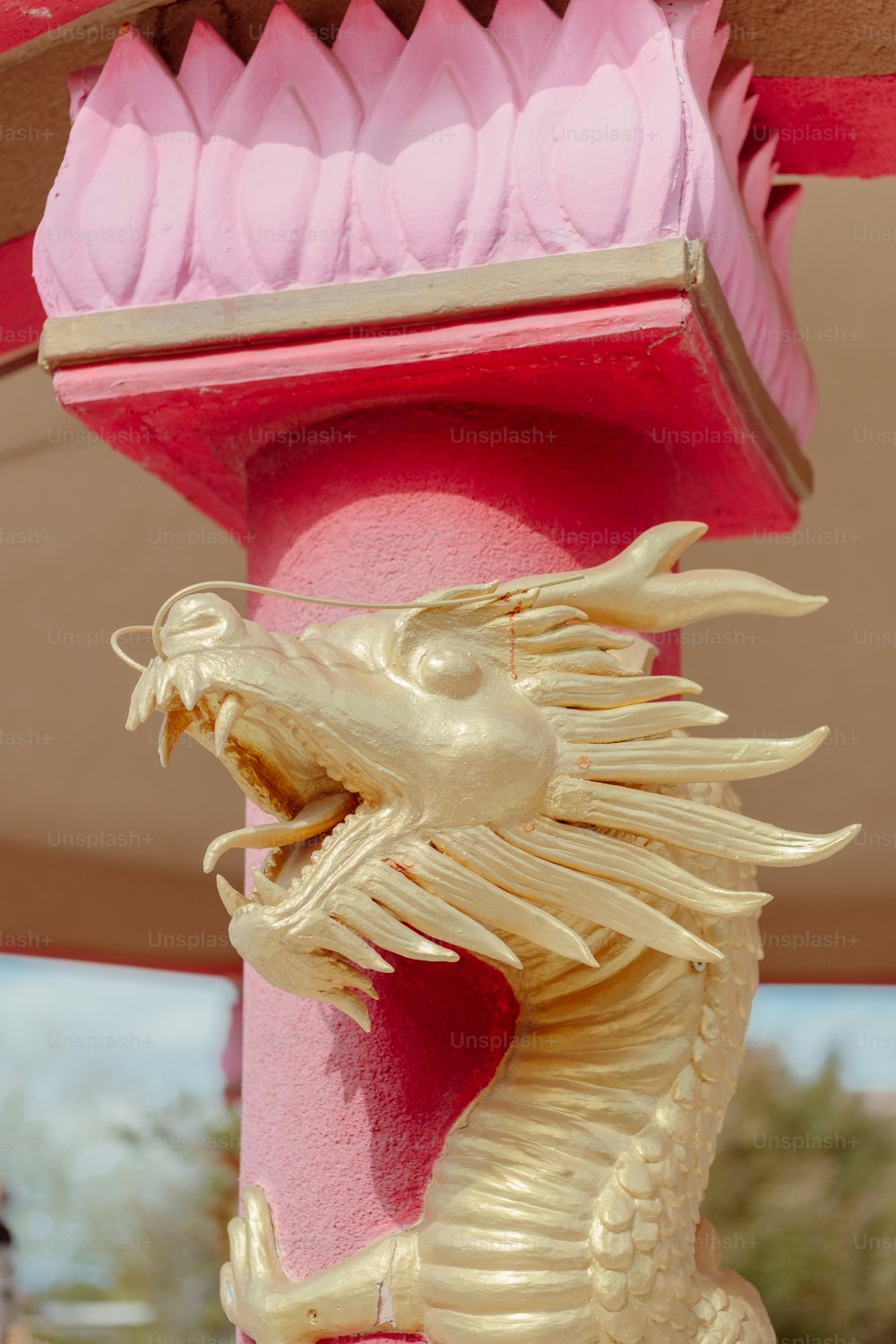 Una statua di drago d'oro seduta sulla cima di un palo rosa