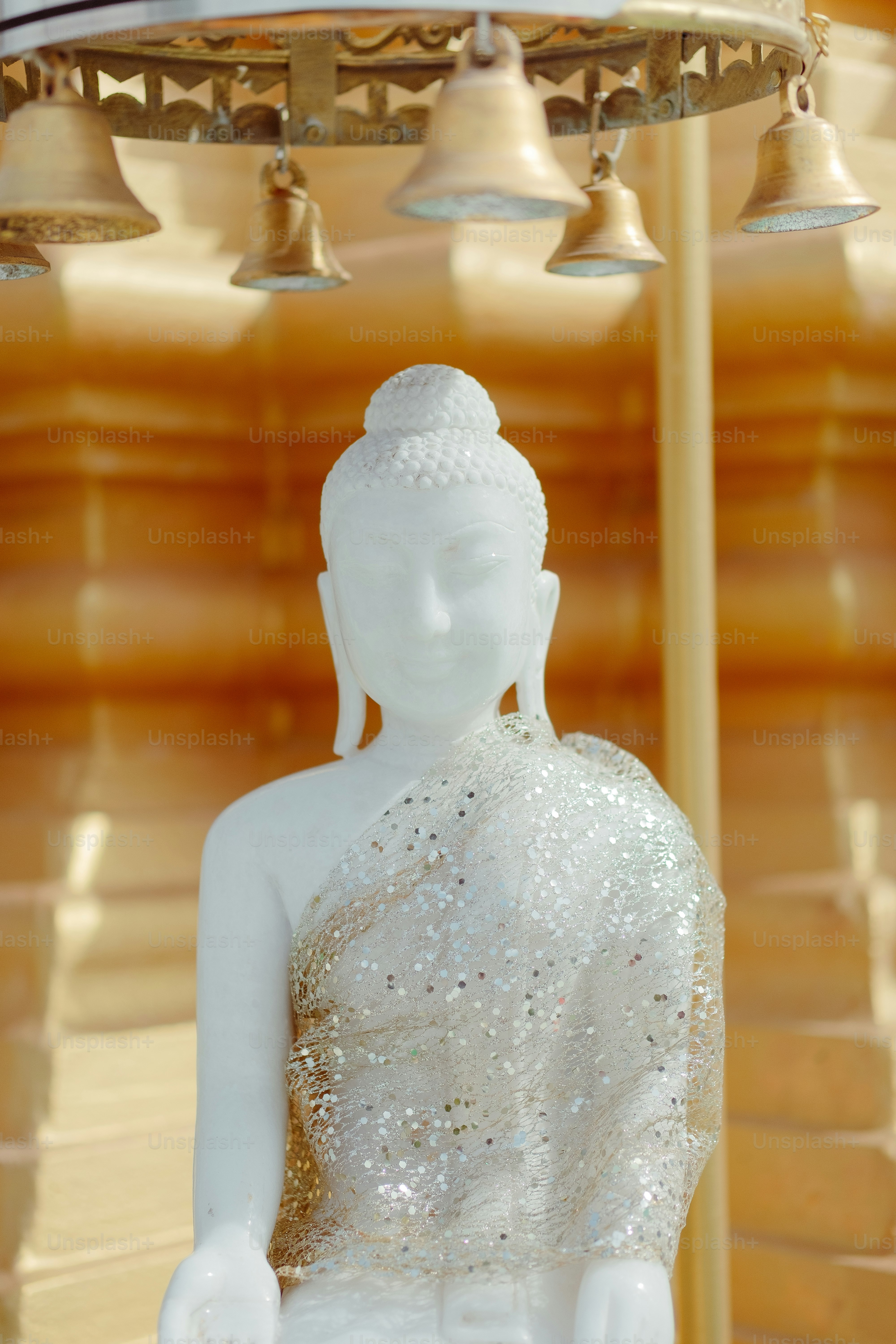 a white buddha statue sitting under a chandelier