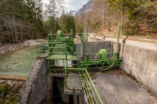 a large green machine sitting next to a river