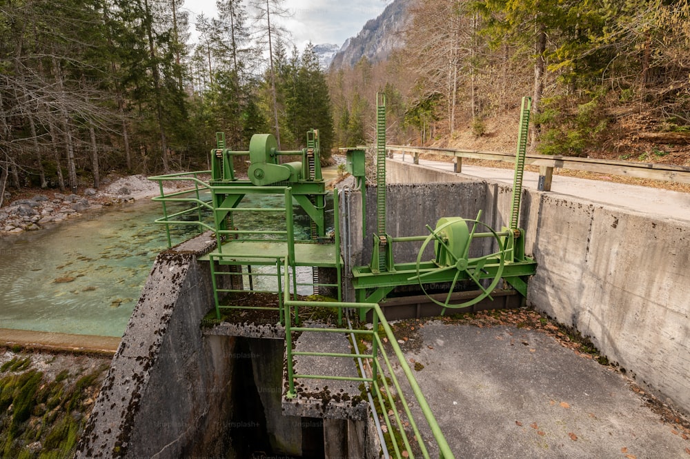 a large green machine sitting next to a river