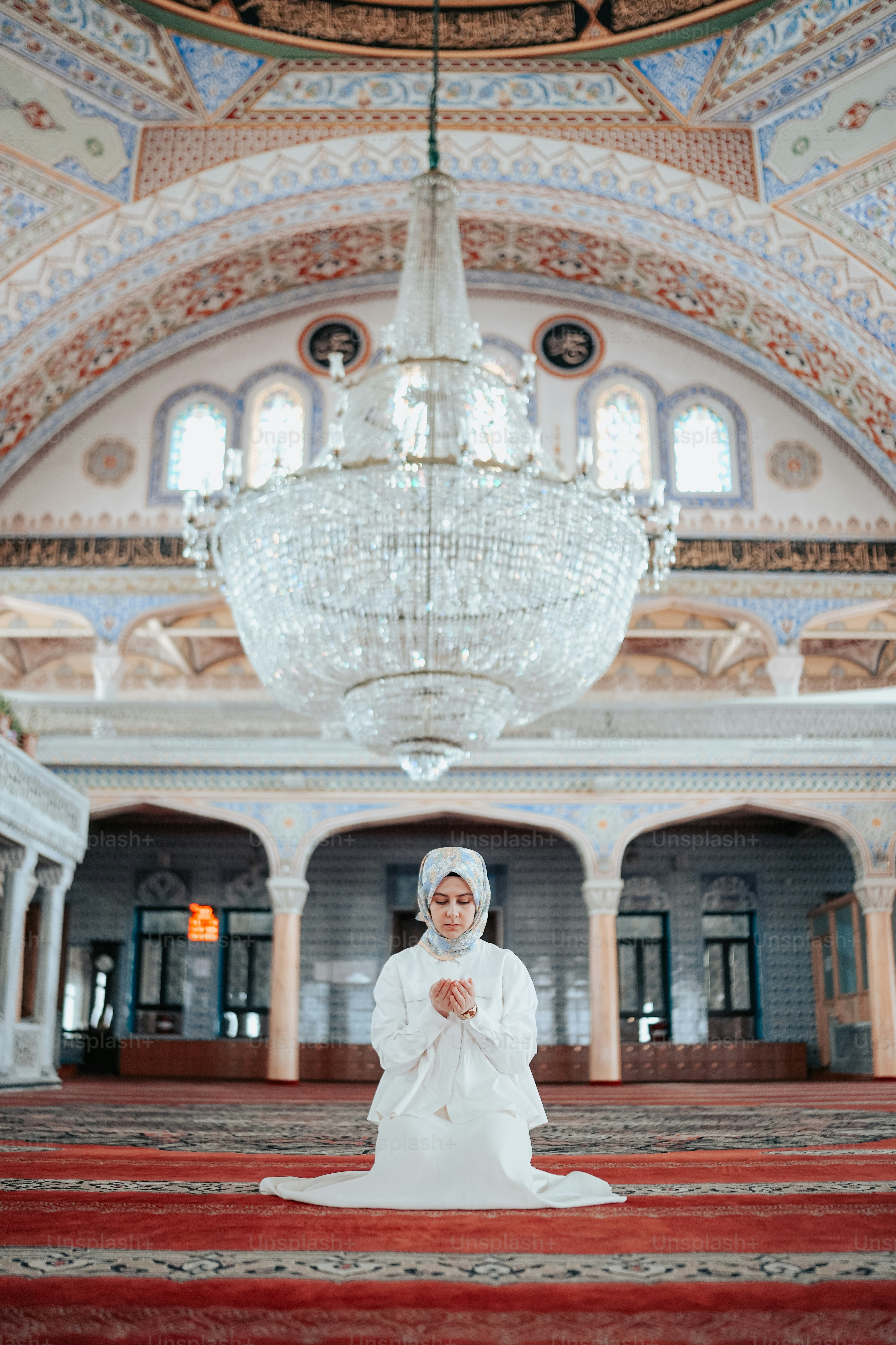 a woman in a white dress standing in a room with chandelier