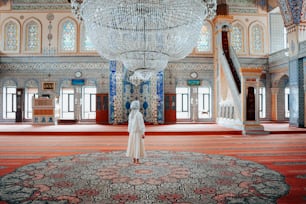 a woman standing in a room with a chandelier