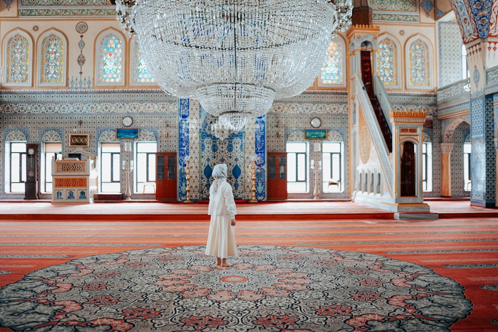 a woman standing in a room with a chandelier