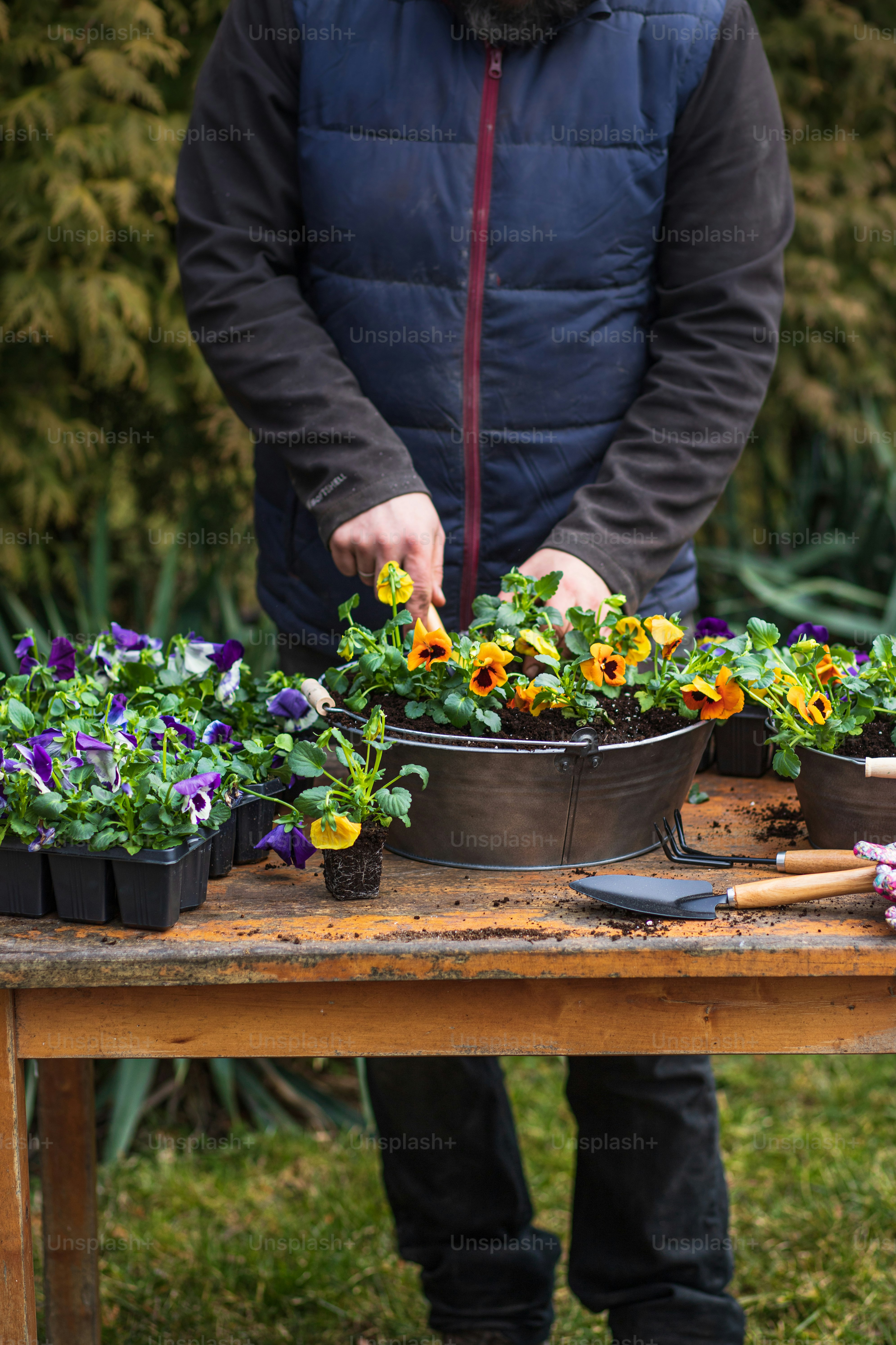 a man standing in front of a table filled with potted plants