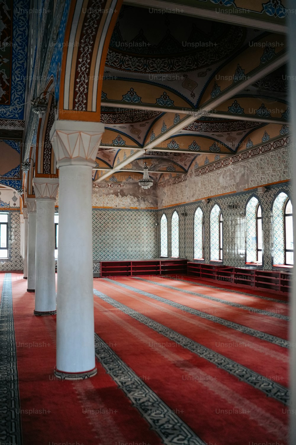 Une grande salle avec tapis rouge et piliers blancs