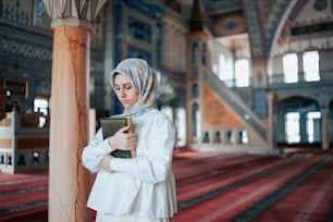 a woman wearing a headscarf is reading a book