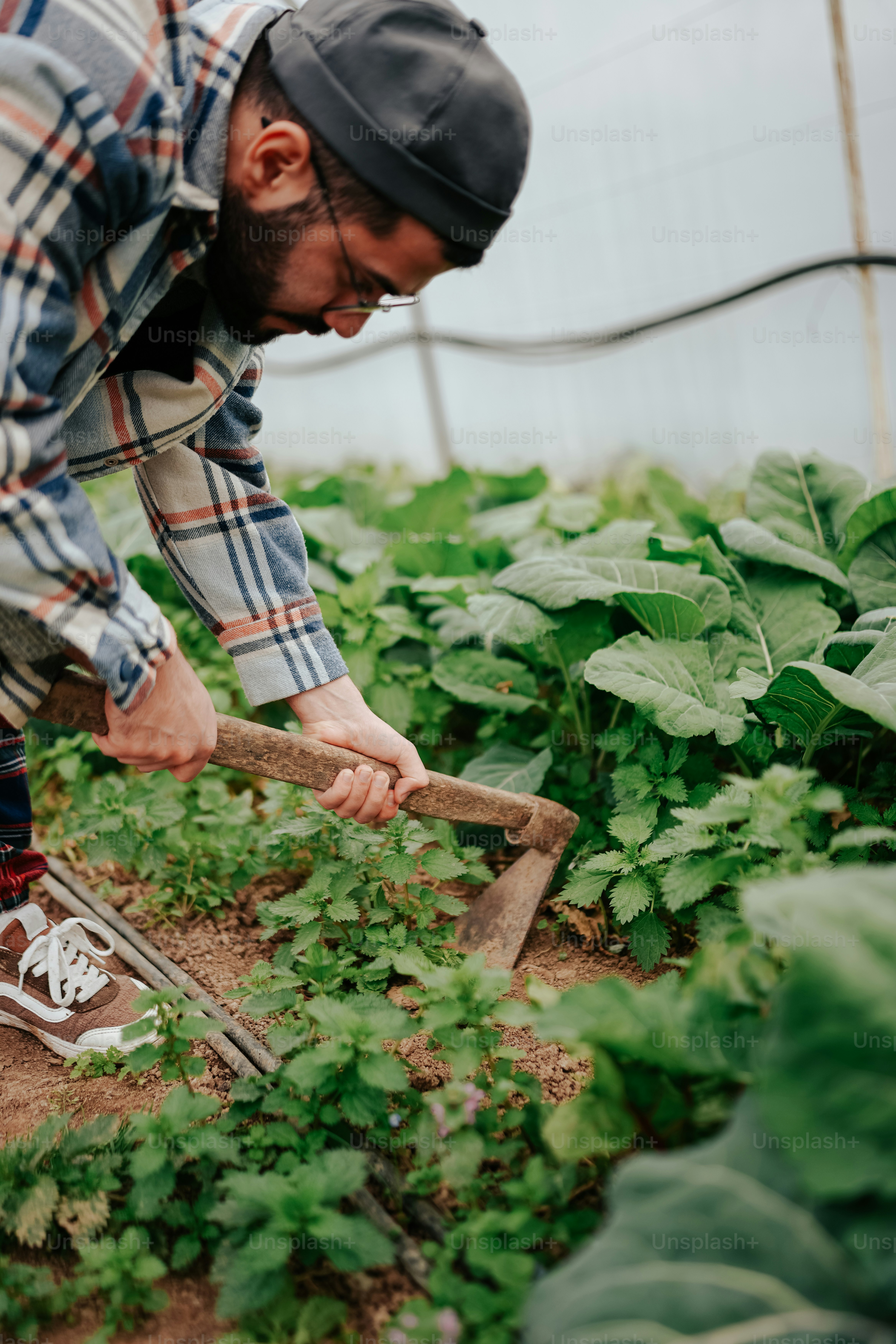 a man in plaid shirt holding a shovel in a garden