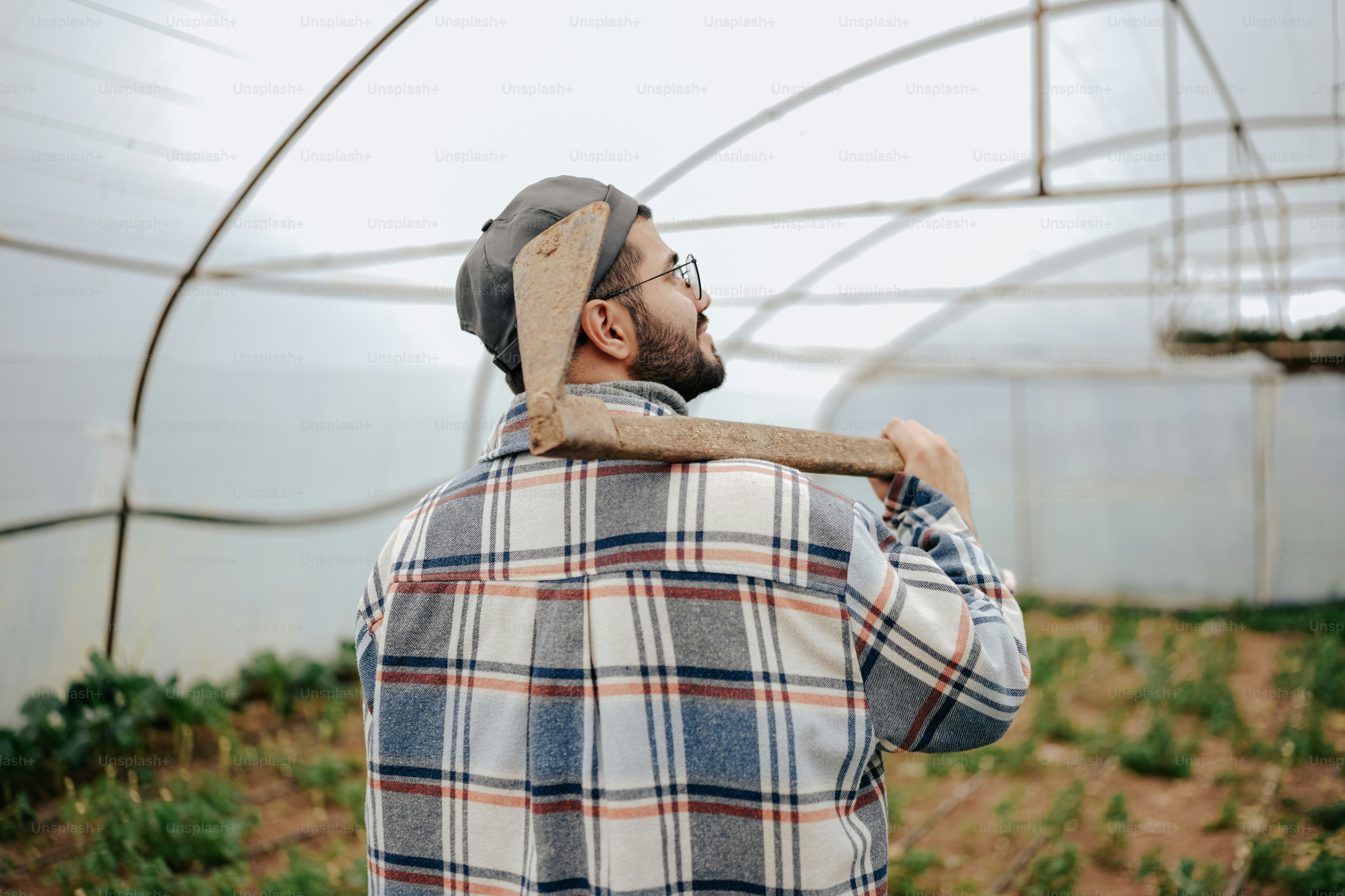 a man holding a stick in a greenhouse