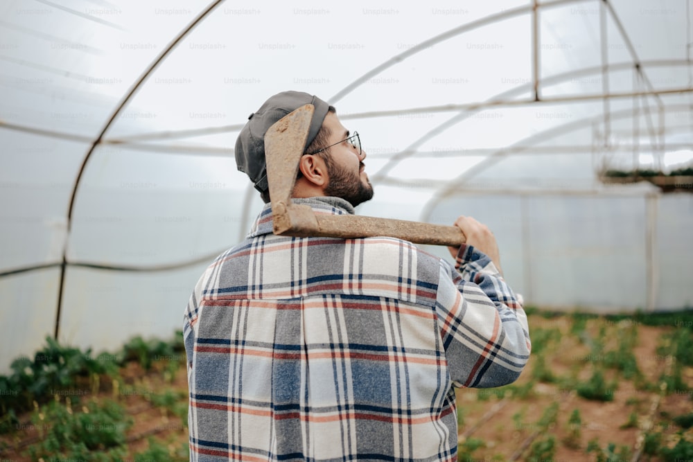 a man holding a stick in a greenhouse