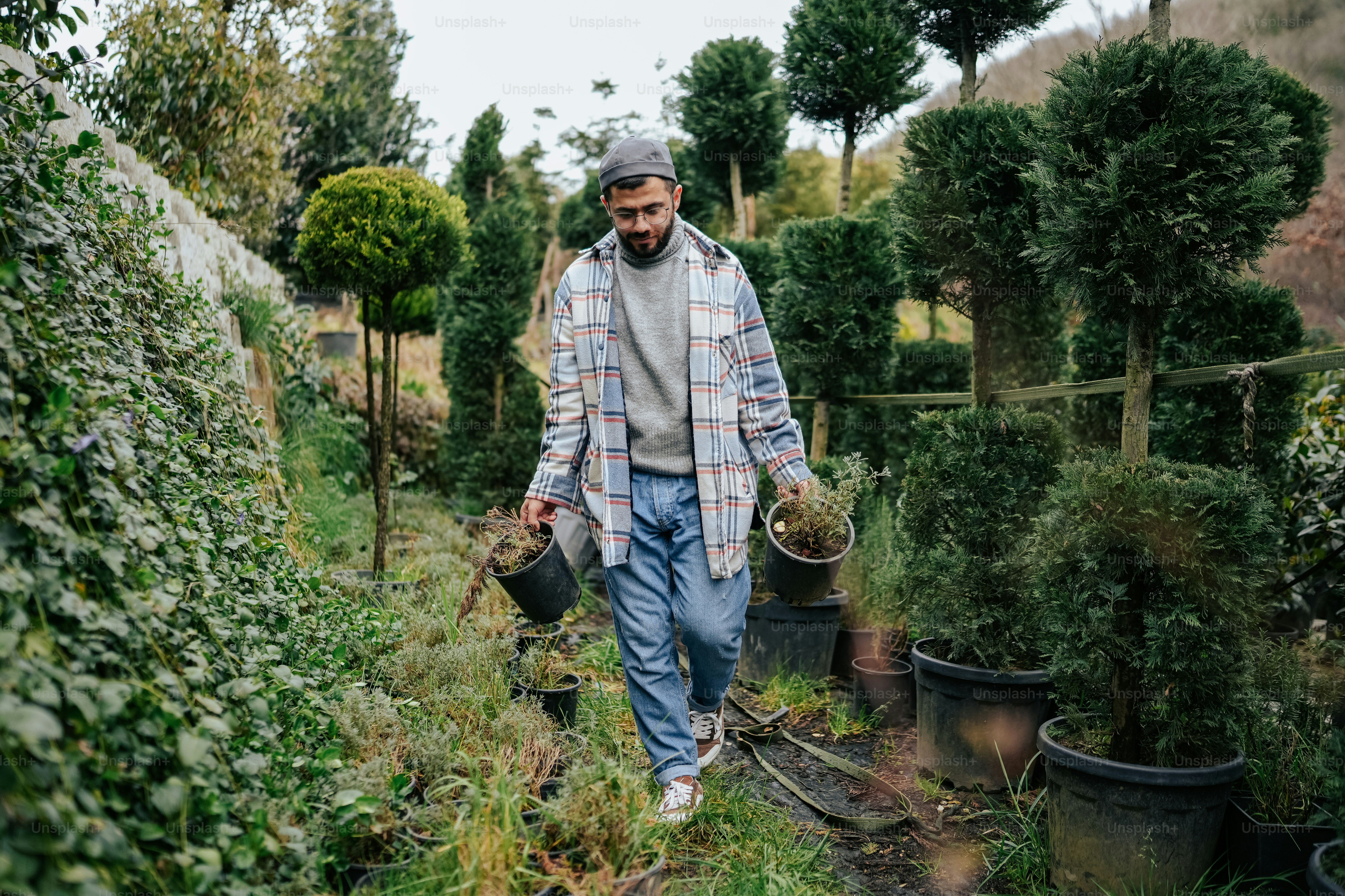 a man walking through a garden filled with potted plants