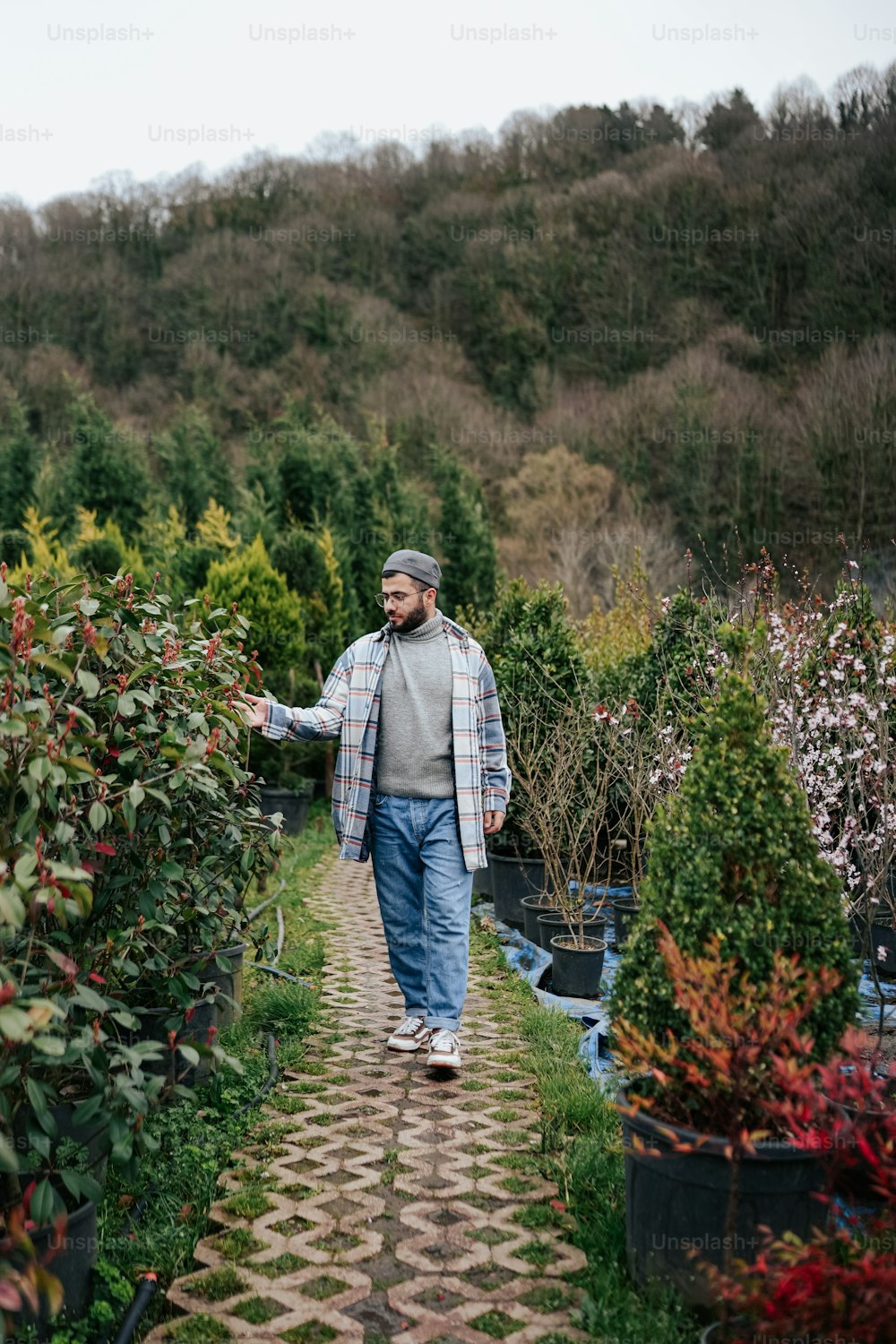a man walking through a garden filled with lots of plants