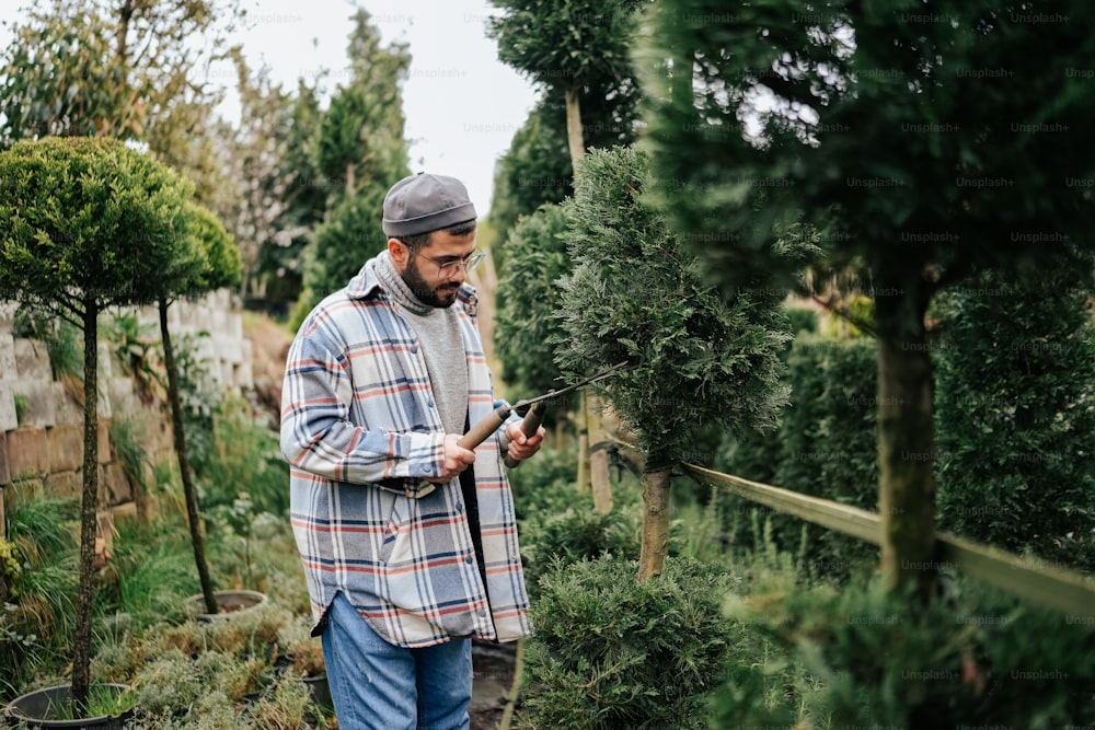 a man standing in a garden holding a cell phone