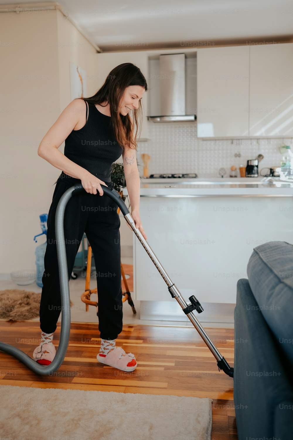 Una mujer está usando una aspiradora para limpiar el piso
